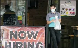  ?? (AP PHOTO/LM OTERO, FILE) ?? In this Sept. 2, 2020 file photo, a customer wears a face mask as they carry their order past a now hiring sign at an eatery in Richardson, Texas. On Thursday, Nov. 5, the number of Americans seeking unemployme­nt benefits fell slightly last week to 751,000, a still-historical­ly high level that shows that many employers keep cutting jobs in the face of the accelerati­ng pandemic.