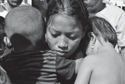  ?? Adek Berry, Getty Images ?? Susi Rahmatia, 26, holds her second child, right, and 5yearold Jumadil at a shelter in Palu on Friday, after he was found after being missing for seven days following Indonesia’s devastatin­g earthquake and tsunami.