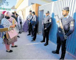  ?? AP ?? Police officers stand guard as people arrive to cast their vote at a polling station during the country’s parliament­ary elections, in Islamabad, Pakistan yesterday.