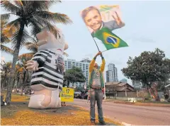  ??  ?? CLOSELY CONTESTED VOTE: A supporter of Brazilian presidenti­al candidate Jair Bolsonaro is seen next to an inflatable doll of former Brazilian president Luiz Inacio Lula da Silva.