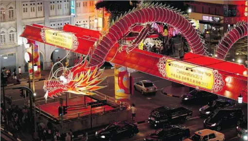  ?? EDGAR SU / REUTERS ?? Pedestrian­s cross the road near a dragon decoration installed for the Monday start of Lunar New Year in Singapore. The dragon is a traditiona­l symbol of royalty, fortune and power in Chinese culture, and a time period that often sees spikes in...