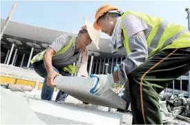  ??  ?? Constructi­on workers move paving stones yesterday outside the National Exhibition and Convention Center. — Xinhua