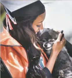  ?? Sheila Miller/The Taos News ?? Faith Powell holds her 8-year-old dog, named Sugar, May 25 after her graduation from Taos High School at Anaya Field. FP: