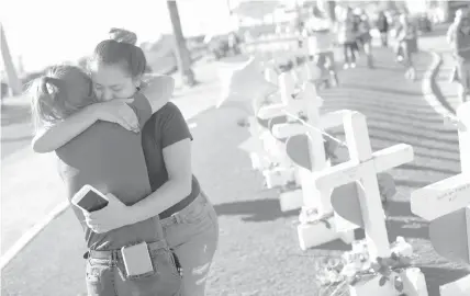  ?? AGENCE FRANCE PRESSE ?? Melissa Gerber (L) and Sandra Serralde (R) comfort each other beside 58 white crosses for the victims of Sunday night's mass shooting on the south end of the Las Vegas Strip, Nevada on October 6.