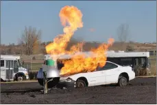  ??  ?? Flames from the liquid propane fire shoot into the air at the tanker and vehicle training props during the demonstrat­ion hosted by the Swift Current Fire Department.