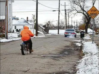  ?? CORNELIUS FROLIK / STAFF ?? A man rides a motorized bicycle along an East Dayton street.