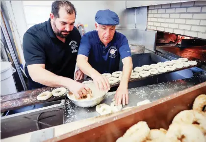 ?? JOHN MAHONEY ?? Owner Joe Morena and his son Robert prepare bagels at their St-Viateur bagel factory last year. The family says their new air purifier will save the Montreal wood-fired bagel.