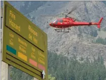  ?? Herald photo by Ian Martens ?? A helicopter takes off behind a sign listing the extreme fire hazard before heading back along Upper Waterton Lake Saturday as crews continued to work to control the wildfire that started Friday afternoon.