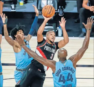  ??  ?? CJ McCollum busca a un compañero defendido por Ja Morant y Anthony Tolliver, de los Grizzlies.