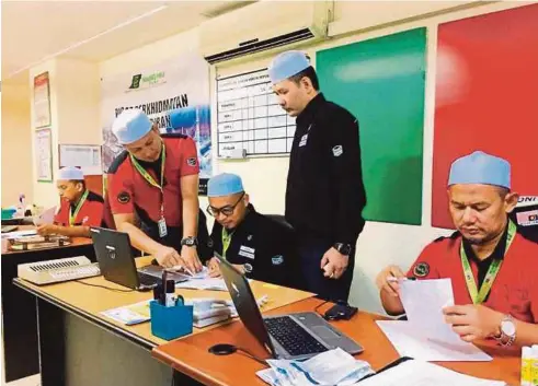  ??  ?? AFFANDI (dua dari kanan) melihat petugas membuat persiapan bagi menguruska­n jemaah haji Malaysia di Pejabat Operasi TH Madinah.