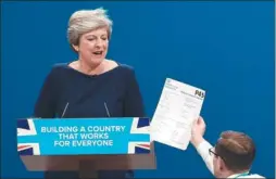  ?? PAUL ELLIS / AGENCE FRANCE-PRESSE ?? A prankster gives a mock P45 (employee leaving form) to Prime Minister Theresa May during Wednesday’s speech in Manchester, England.