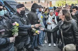  ?? Alberto Pizzoli AFP/Getty Images ?? WOMEN HAND flowers to police officers during a protest Friday in Rome. Similar demonstrat­ions against Italy’s so-called Green Pass took place in other cities.