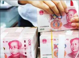  ?? AFP ?? A bank employee counts piles of 100-yuan notes. The yuan is used for approximat­ely 10 per cent of the total trade between Cambodian and China.