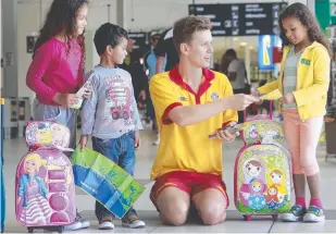  ??  ?? Jordan Harrison hands out safety tips to Yasmin, Jean and Danielle Almeida from Sydney back in 2013 when surf lifesavers were a regular sight at Gold Coast Airport.