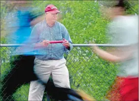  ?? TIM MARTIN/THE DAY ?? Fitch High School’s Rich Kosta, now in his 41st season as a track and field coach, holds a relay baton while watching his boys’ team go through drills during a recent practice. Kosta is a finalist for national coach of the year honors.