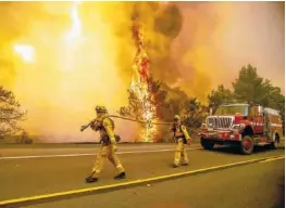  ?? AP PHOTO BY NOAH BERGER ?? Firefighte­rs try to stop a wildfire Sunday as wind drives embers across Highway 20 near Clearlake Oaks, Calif.