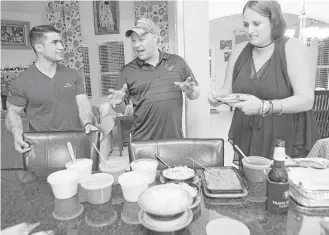  ?? Elizabeth Conley photos / Houston Chronicle ?? Mohammed “Jay” Younus Yousafzoy talks Texas barbecue with Jordan Step as Step’s wife, Meghan, prepares a plate at a gathering for Yousafzoy to meet his neighbors in southeast Houston.