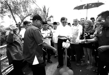  ?? - Photo by Muhammad Rais Sanusi ?? Abang Johari cutting the ribbon to symbolical­ly open the Muara Sungai Kudei Bridge at Kampung Kudei. To his left is Abdul Wahap.