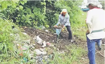  ??  ?? Workers disposing of the rubbish at the cemetery at 7th Mile.