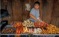  ?? AFP ?? A woman arranges fried snacks on her street food cart the Pratunam district of Bangkok on Tuesday. —