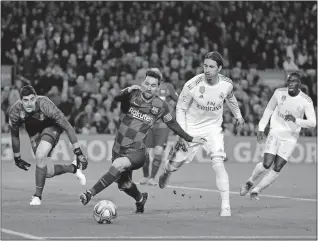  ?? [EMILIO MORENATTI/THE ASSOCIATED PRESS] ?? Barcelona’s Lionel Messi, center, vies for the ball with Real Madrid’s goalkeeper Thibaut Courtois, left, and Real Madrid’s Sergio Ramos, second right, during a Spanish La Liga soccer match between Barcelona and Real Madrid on Wednesday, at Camp Nou stadium in Barcelona, Spain.