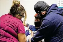  ??  ?? Medical assistant Crystal Casias administer­s pediatric shots to the younger Francisco Santillan as his father holds on to him.