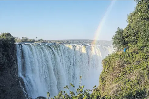  ?? PHOTOS BY AFP ?? A tourist enjoys a view of waterfalls from the ‘Devil’s Cataract’ where water rumbles down at height of 73 metres at Victoria Falls.