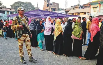  ??  ?? A soldier stands guard as women queue to cast their votes outside a polling station during the Madhya Pradesh assembly election in Jabalpur yesterday.