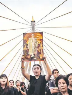  ??  ?? File photo shows a woman holding aloft a picture of the late King Bhumibol as people gather to commemorat­e his birthday on top of Bhumibol Bridge in Bangkok. — AFP photo