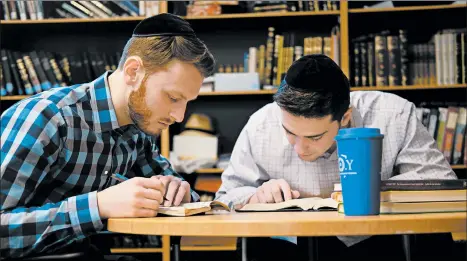  ?? LUIS ANDRES HENAO/AP ?? Yeshiva University students Aaron Heideman, left, and Marc Shapiro study at the university’s library Thursday in New York. Heideman said the president’s order will help his friends at secular universiti­es who have run into problems.