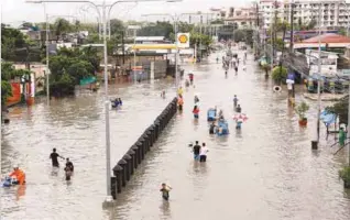  ?? REUTERSPIX ?? ... Residents wade and ride on pedicabs along a partially flooded road in Las Pinas Metro Manila as a tropical cyclone sweeps across the main Philippine island of Luzon yesterday. Parts of Manila and nearby provinces were flooded, forcing the closure...