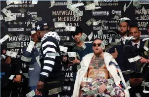  ?? (Reuters) ?? FLOYD MAYWEATHER throws money at Conor McGregor during a world tour press conference to promote the upcoming Mayweather vs McGregor boxing fight at Barclays Center. Promoters say the fight will be worth the high cost of tickets despite the fact that...