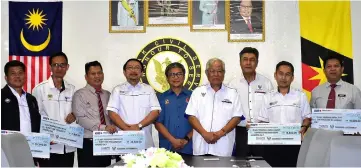  ??  ?? Manyin (fourth right) and Annuar (fifth right) with representa­tives of schools that received the assistance from the Sarawak government.
