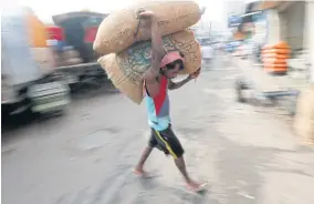  ??  ?? A worker carries a sack of rice at the main market in Colombo.