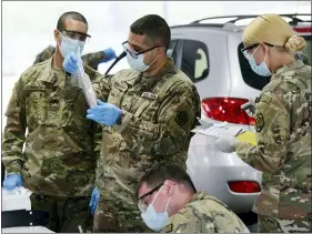  ?? JOE LEWNARD — DAILY HERALD VIA AP ?? Members of the Illinois National Guard work with the public at the state’s new drive-thru COVID-19testing facility at Rolling Meadows High School Friday, May 22, 20202in Rolling Meadows, Ill. The test is self-administer­ed by the person being tested, and the test kits are passed through the partially-opened car window.