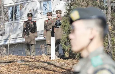  ?? AP PHOTO ?? North Korean soldiers look at the South side as a South Korean stands guard near the spot where a North Korean soldier crossed the border on Nov. 13 at the Panmunjom, in the Demilitari­zed Zone, South Korea on Monday.