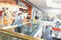  ?? PHOTOS BY JOE RONDONE/THE COMMERCIAL APPEAL ?? Sheldra Knox works to disinfect the hand rails at Oak Court Mall on its second day after reopening.