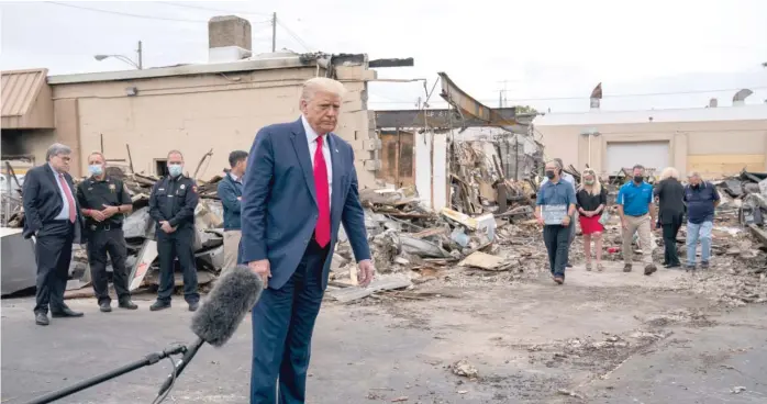  ?? EVAN VUCCI/AP ?? President Donald Trump tours an area Tuesday that was damaged after protests against the police shooting of Jacob Blake in Kenosha, Wisconsin, turned violent.