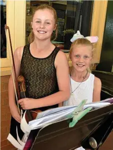  ??  ?? Gabrielle Reimers (left) and her sister Eve Reimers show their skills on the violin at the community fair.