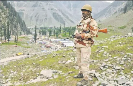  ?? NITIN KANOTRA/ HT ?? A paramilita­ry personnel standing guard at a vantage point overlookin­g the base camp in Baltal, 15 km from Sonamarg, on Wednesday, as the first batch of pilgrims arrived for this year’s Amarnath Yatra. Security has been tightened for the visit to the...