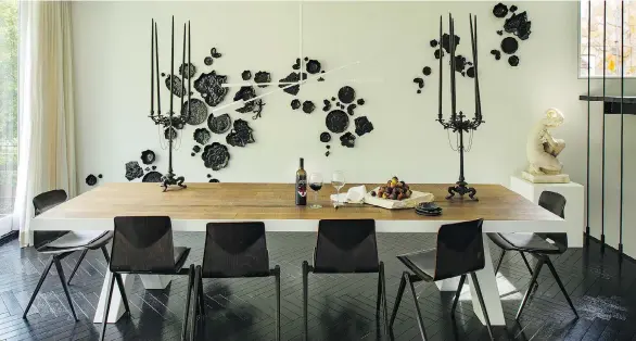  ?? PHOTOS: JOHN MCDONNELL/THE WASHINGTON POST ?? Designer Darryl Carter designed the 11-foot dining table, made of 100-year-old oak and metal, which is surrounded by Midcentury Modern dining chairs. The black ceramic abstract art installati­on on the wall from French artist Sam Baron has both nature and whimsy: If you look closely, you will see lily pads, a lizard and a frog.