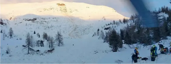  ??  ?? I soccorsiIl luogo della tragedia: sul fondo la grande traccia lasciata dalla valanga che aveva un fronte di 200 metri. Sulla destra i tre ragazzi rimasti illesi e le loro motoslitte La vicenda● L’altro ieri nel tardo pomeriggio una valanga si è staccata dai monti di Bienno, a