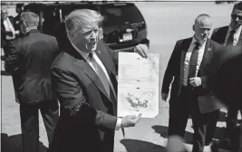  ?? [CAROLYN KASTER/THE ASSOCIATED PRESS] ?? President Donald Trump shows off a a copy of two maps of Syria as he departs from Air Force One on Friday at Palm Beach Internatio­nal Airport in West Palm Beach, Fla. One map shows the high point of Islamic State control in Syria, the other the situation today.