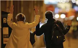  ?? — AFP ?? People raise their hands as they walk towards the police at the site of the shooting at Champs Elysees, Paris, on Thursday.