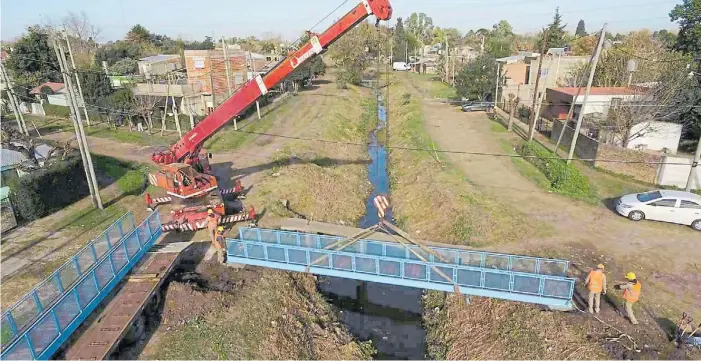  ??  ?? Colocación. La semana pasada uno de los puentes fue instalado en Italia y Sarratea, Claypole. Al lado se ve la peligrosa pasarela de cemento usada para cruzar el arroyo San Francisco.