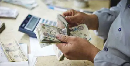  ??  ?? A man counts Egyptian pounds banknotes at a foreign currency exchange bureau in Cairo. It is the common perception that the developmen­t of Islamic banking in Egypt is being held back by hesitant policies by the central bank to develop a solid regulation and also by the government’s indecisive­ness on how to deal with the industry as a whole.