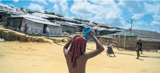  ?? CHANDAN KHANNA/AFP/GETTY IMAGES ?? A young Rohingya refugee pours water on himself to escape the heat in Kutupalong camp in Ukhia, Bangladesh, Thursday.