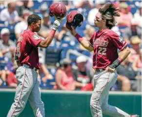  ?? (Photo by Nati Harnik, ?? Florida State's Drew Mendoza (22) celebrates with J.C. Flowers after scoring on a onerun single by Steven Wells in the second inning of Monday's game against Cal State Fullerton in Omaha, Neb.