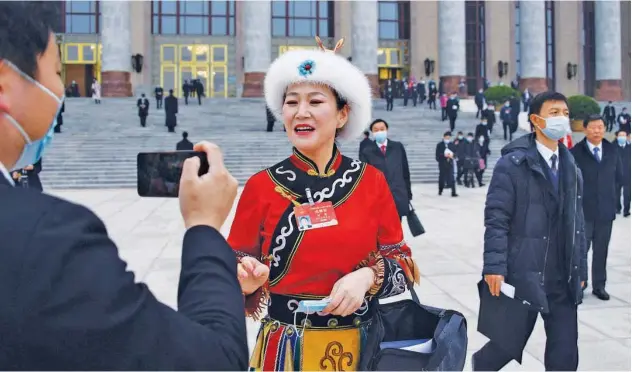  ?? Agence France-presse ?? ↑
An ethnic minority delegate poses for photos outside the Great Hall of the People in Beijing on Friday.