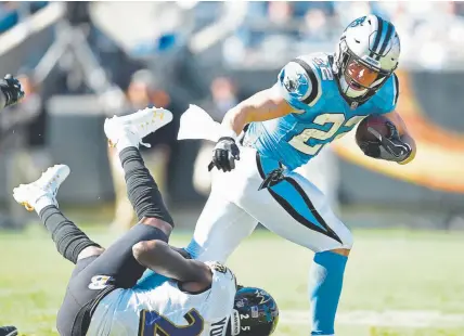  ?? Grant Halverson, Getty Images ?? Carolina Panthers running back Christian McCaffrey runs through Tavon Young of the Baltimore Ravens on Sunday. McCaffrey ran for an 11yard touchdown and caught a 6yard pass from Cam Newton for another.